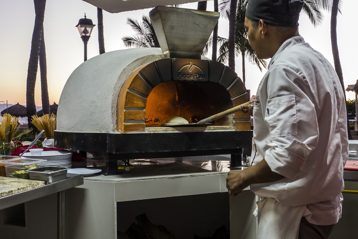 Pizza maker working beside a wood-fired oven